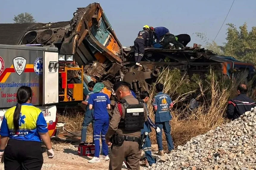 View of the Nakhon Ratchasima train wreckage showing a collapsed yellow construction crane and derailed passenger carriages in Sikhio, Thailand.