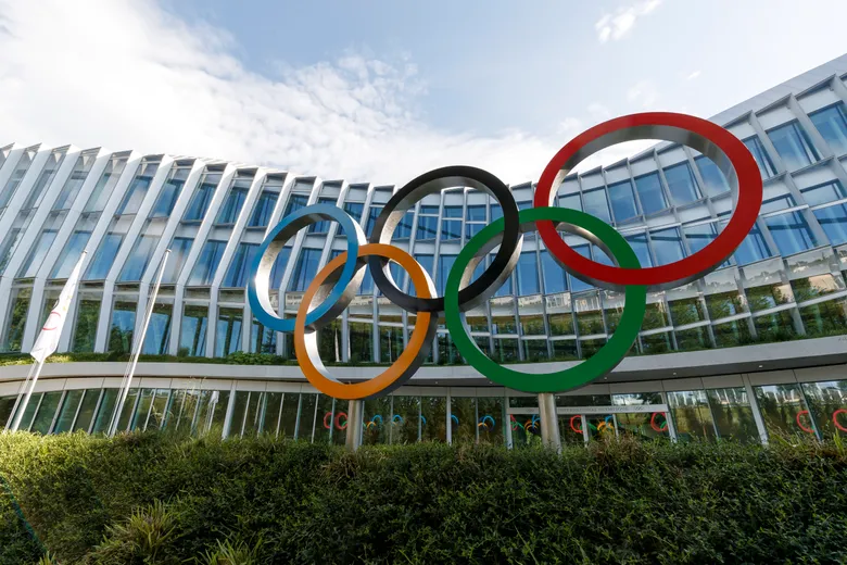 Close-up of the Olympic rings at the IOC headquarters in Lausanne, Switzerland, against a clear blue sky.