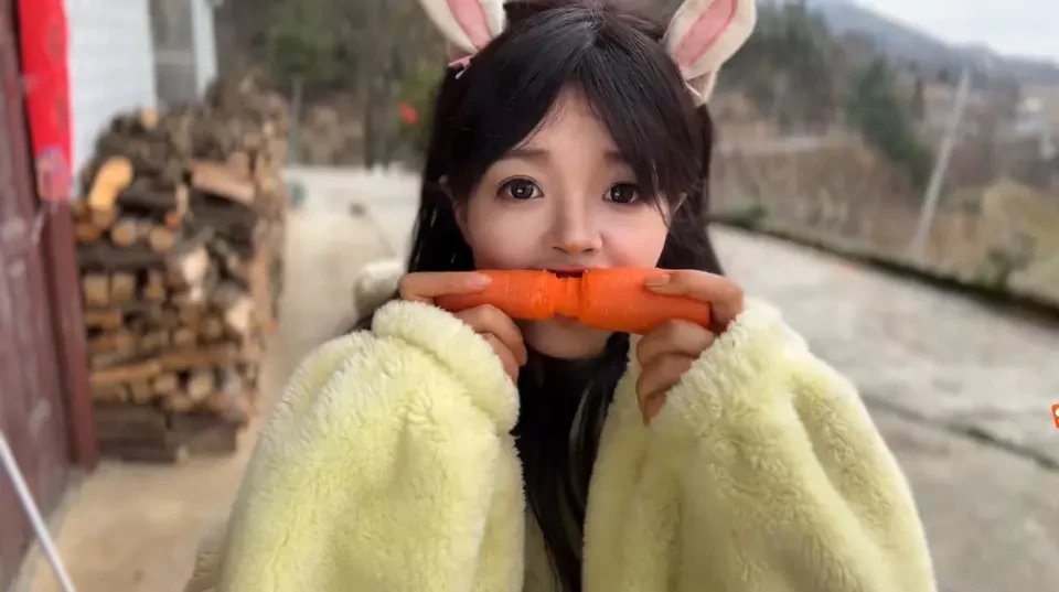 A close-up of Chinese creator Chen Qin holding a bright orange carrot.