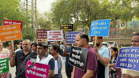 Hundreds of parents holding placards and fee receipts protesting against fee hikes outside the Directorate of Education office in Delhi.